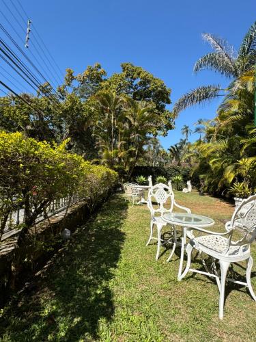 a row of white chairs and tables on the grass at Pousada Crystal Palace in Petrópolis