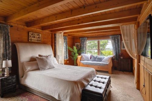 a bedroom with a bed and a couch and a window at Look to the Mountains: Gunstock Acres Log Cabin in Gilford