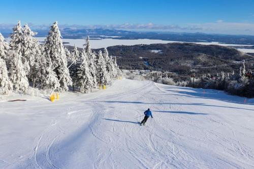 a person is skiing down a snow covered slope at Look to the Mountains: Gunstock Acres Log Cabin in Gilford