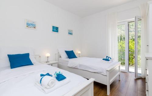 a white bedroom with two beds and a window at Villa Kate - outdoor pool, 4 bedrooms, free parking in Dubrovnik