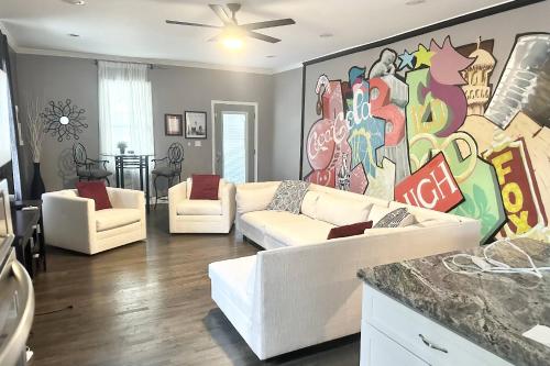 a living room with white couches and a mural at Adair Park Bungalow in Atlanta