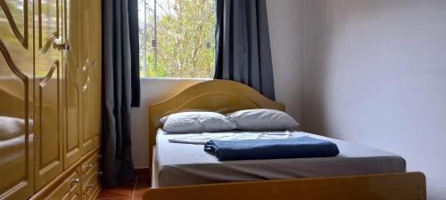 a small bed with two pillows and a window at Paz e descanso Chacara Meu Morrinho in Mairiporã