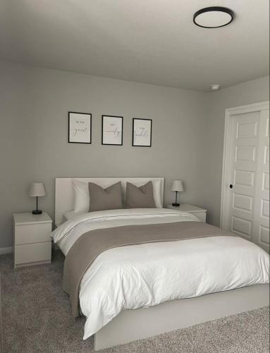 a bedroom with a large bed with three pictures on the wall at Hidden beautiful Modern Apartment in Entebbe