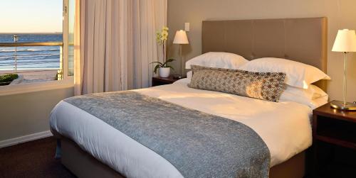 a bedroom with a bed with a view of the ocean at Lagoon Beach Hotel & Spa in Cape Town