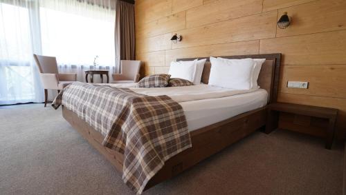 a bedroom with a large bed with a wooden wall at Комплекс Белите скали in Gaytaninovo
