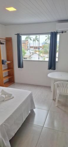 a room with a bed and a table and a window at Suíte Com Vista Privilegiada poucos minutos Vila Germânica Oktoberfest in Blumenau