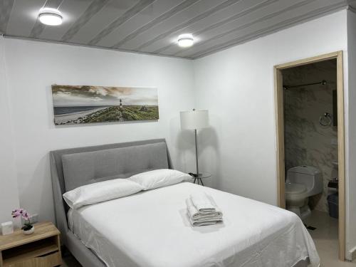 a white bedroom with a bed and a lamp at Hotel Orduz Centro Histórico de Cali in Cali