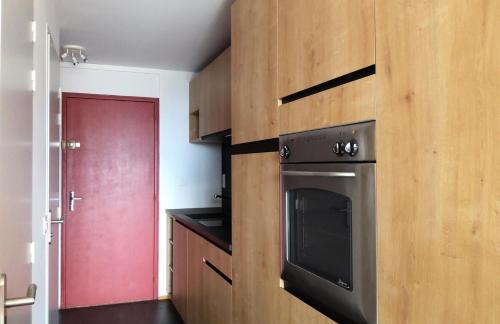 a kitchen with a stove and a red door at Résidence Les Arolles - Studio cabine 5 personnes agréable et bien aménagé à Arc 1600 en centre station et proche des pistes MAE-2139 in Arc 1600