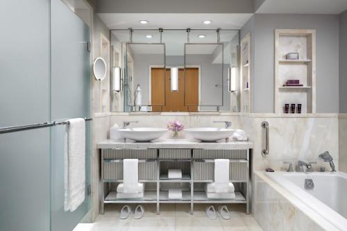 a bathroom with two sinks and a tub and a mirror at The Ritz-Carlton, Toronto in Toronto