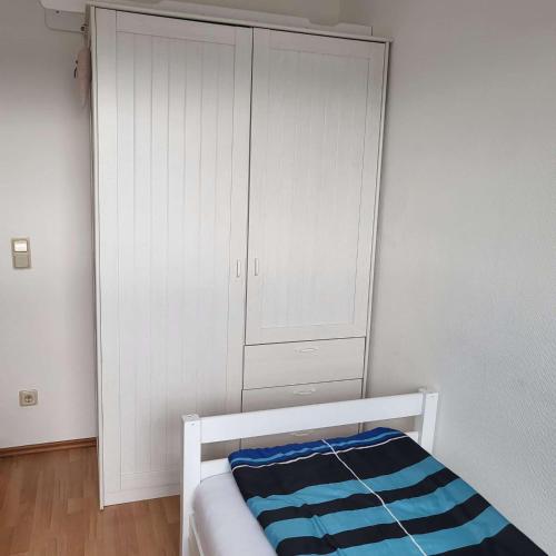 a bedroom with a bed and a white cabinet at Bielsteiner Heideglück in Wiehl