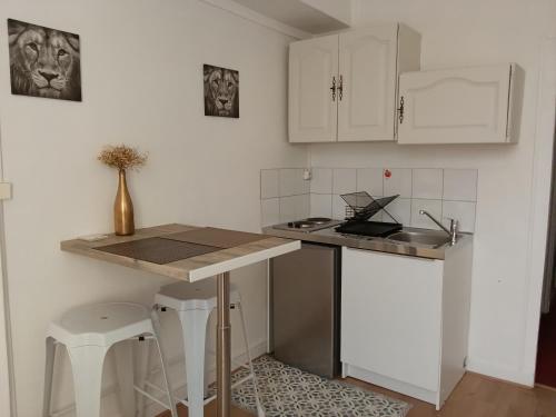 a kitchen with white cabinets and a table and stool at Appartement sur la route touristique du champagne in Sézanne