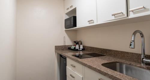 a kitchen with a sink and a microwave at Prestige Oceanview Hotel Prince Rupert in Prince Rupert