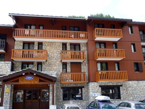 un bâtiment avec balcon et voitures garées dans un parking dans l'établissement Résidence Les Jardins De Val - Appartement 2 pièces pour 4 personnes à Val d'Isère à 350m du centre du village et 450m des pistes MAE-2994, à Val dʼIsère