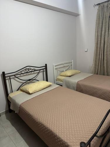 two twin beds in a room with white walls at Margaret home in Kalývia