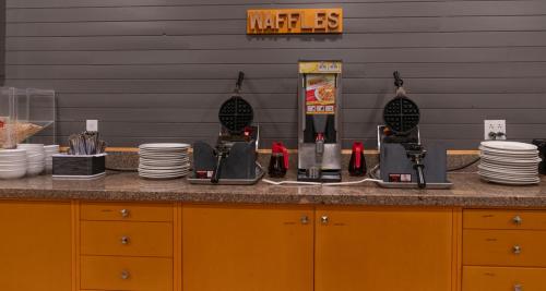 a counter with a coffee maker and plates on it at Prestige Oceanview Hotel Prince Rupert in Prince Rupert