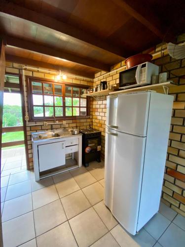 a kitchen with a refrigerator and a stove at Pousada Jardim da Lagoa in Garopaba