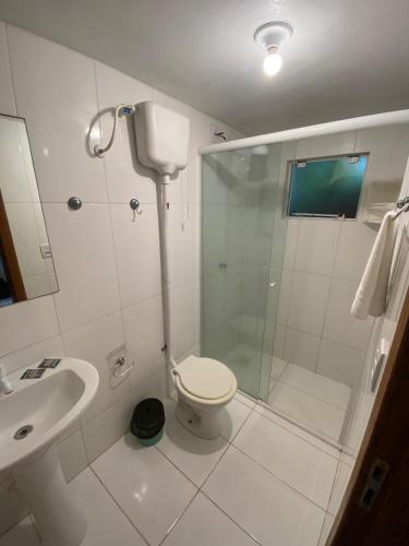a bathroom with a shower and a toilet and a sink at Pousada Jardim da Lagoa in Garopaba