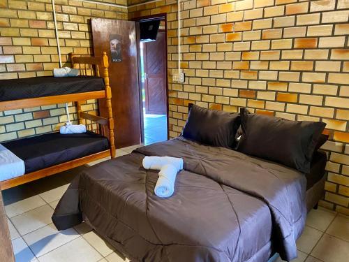 a bed in a room with a brick wall at Pousada Jardim da Lagoa in Garopaba