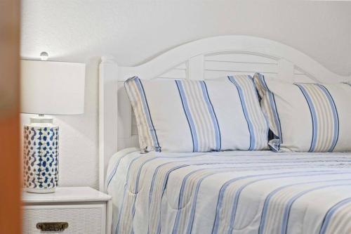 a white bed with blue and white striped pillows at Dolphin Cove Waterfront Home with Dock in Saint Augustine