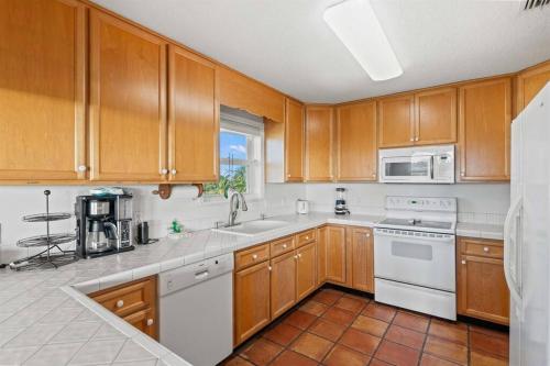 a kitchen with wooden cabinets and white appliances at Dolphin Cove Waterfront Home with Dock in Saint Augustine