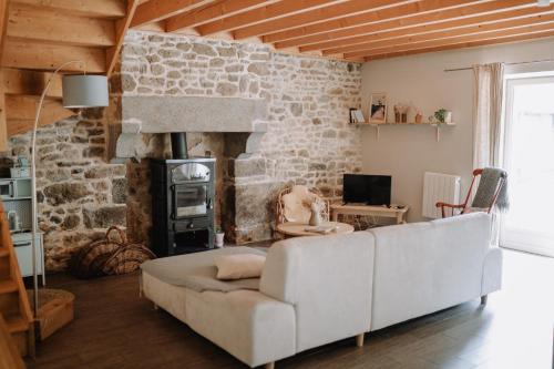 un salon avec un canapé blanc et une cheminée dans l'établissement Les Maisons du Tuly, au Tronchet