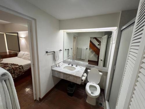 a bathroom with a sink and a toilet and a bed at Islas del Sol in Mazatlán