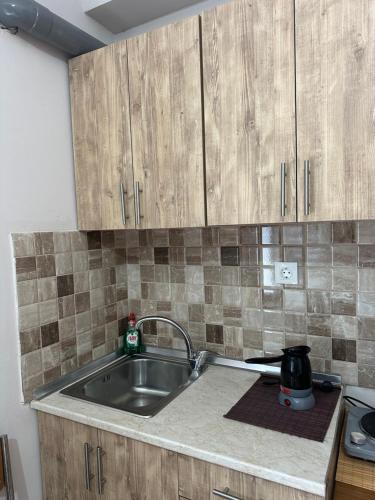 Una cocina con fregadero y armarios de madera. en Margaret home, en Kalývia