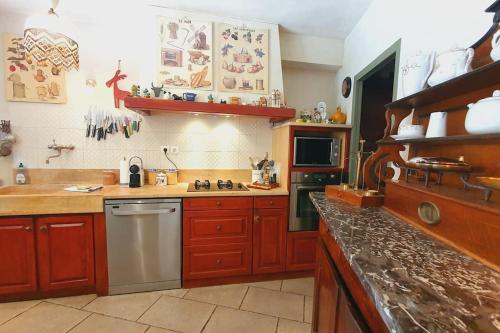 a kitchen with wooden cabinets and a counter top at Maison de Village en Camargue Parking Clim Wifi - ROSSIconciergerie - Linge inclus in Saint-Laurent-dʼAigouze
