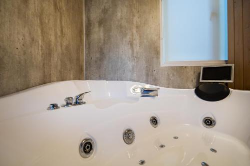 a white bath tub with a computer on top of it at H15, Sauna- en Wellnesschalet geschikt voor 2 personen in Epe