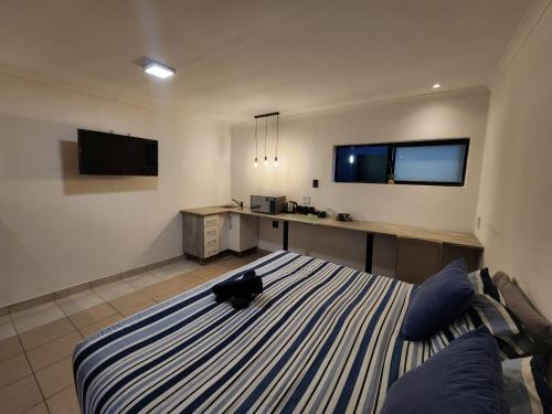 a room with a bed and a desk with a tv at East Park Inn in Polokwane