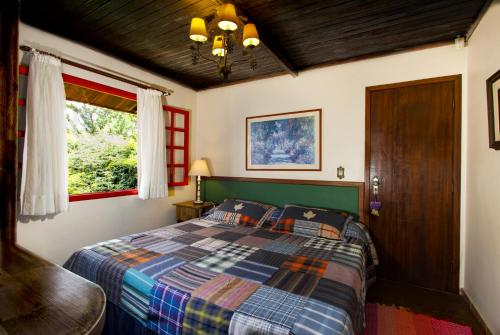 a bedroom with a bed with a checkered blanket at Pousada Benevento in Campos do Jordão
