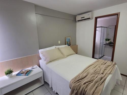 a small bedroom with a white bed and a side table at Apartamento Ponta Verde in Maceió