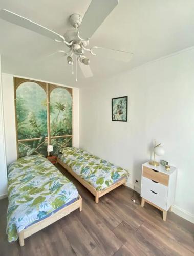 une chambre avec deux lits et un ventilateur de plafond dans l'établissement Coquet appartement au Mourillon, à Toulon