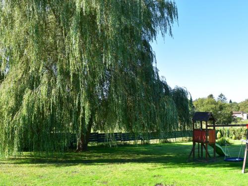 a weeping willow tree and a swing set in a park at Spacious Family Haven in Kröpelin in Kröpelin