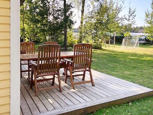 three chairs and a wooden table on a deck at 6 person holiday home in MELLBYSTRAND-By Traum in Mellbystrand