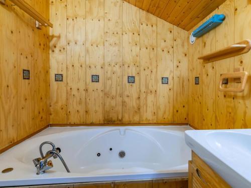 La salle de bains est pourvue d'une baignoire et de murs en bois. dans l'établissement Résidence Gaillard - GAILLARD 05 MAE-4311, à Les Allues