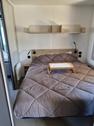 a bedroom with a bed with a book on it at Mobil Home 6 Personnes Camping 5 étoiles Montalivet in Vendays-Montalivet