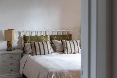 a white bed with pillows and a lamp on a night stand at Dimora San Donato in Casole dʼElsa