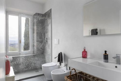 a bathroom with a toilet and a sink and a window at Dimora San Donato in Casole dʼElsa