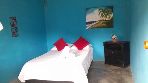 a blue bedroom with two beds with red pillows at Eco Hotel Amanecer Tayrona in El Zaino
