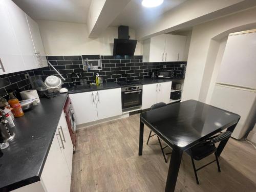 a kitchen with a table and a black counter top at Easy home in Manchester