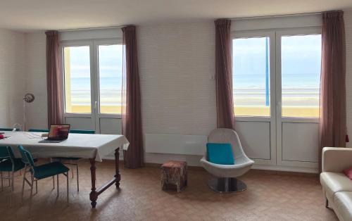 un salon avec une table, des chaises et des fenêtres dans l'établissement unobstructed beachfront view apartment, à Bray-Dunes