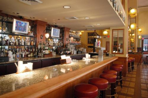 a bar with bar stools and a counter with alcohol at Crowne Plaza New Orleans French Qtr - Astor by IHG in New Orleans