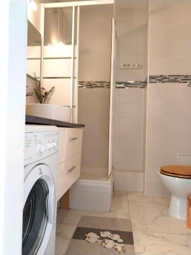 une machine à laver dans une salle de bain avec toilettes dans l'établissement julia, à Alfortville