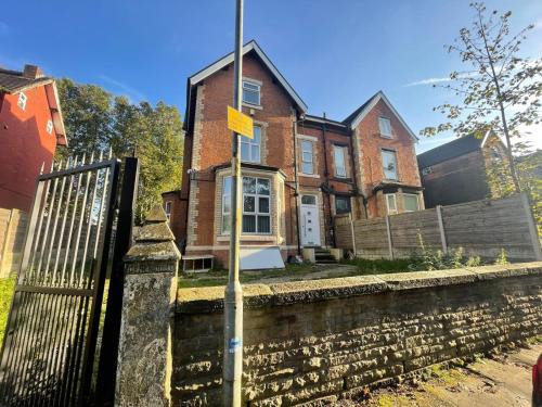 a brick house with a yellow sign on a fence at Easy home in Manchester