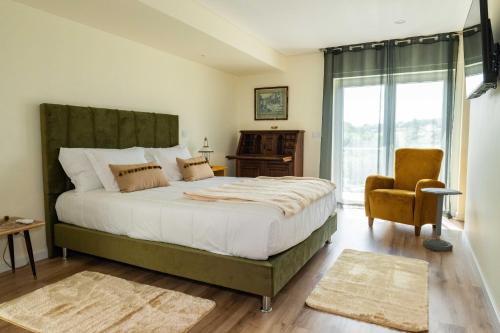 a bedroom with a large bed and a chair at Vó Laide in Carvalhal da Loiça