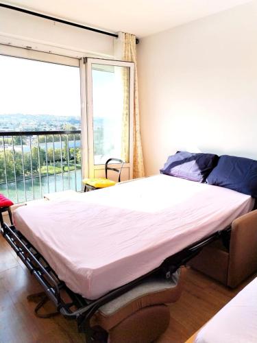 un lit dans une chambre avec une grande fenêtre dans l'établissement julia, à Alfortville