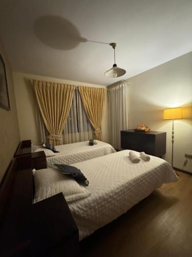 a bedroom with two white beds and a window at Casona tupuraya in Cochabamba