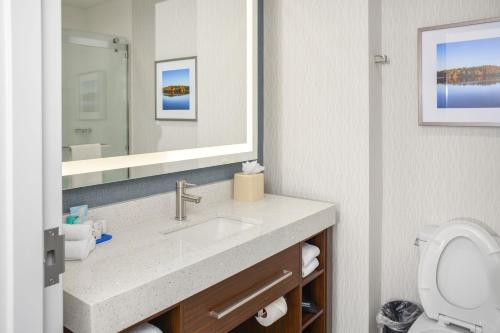 a bathroom with a sink and a toilet and a mirror at Four Points by Sheraton Fayetteville Fort Bragg in Fayetteville