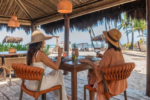 two women sitting at a table on the beach at Rumah Pousada in Barra Grande